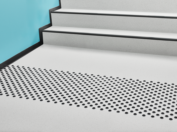 Aufmerksamkeitsfeld mit schwarzen Noppen vor einer Treppe mit Treppenkanten nach DIN 18040‑1