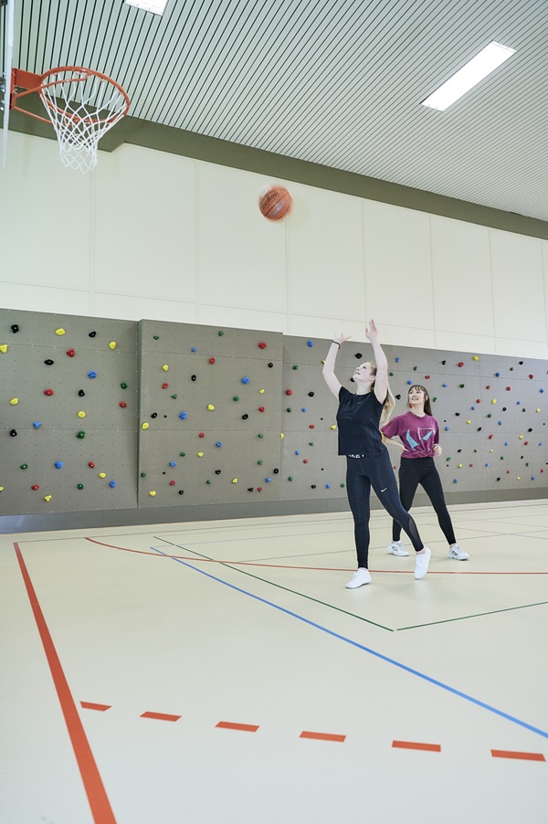 Zwei Mädchen in einer Turnhalle beim Korbwurf