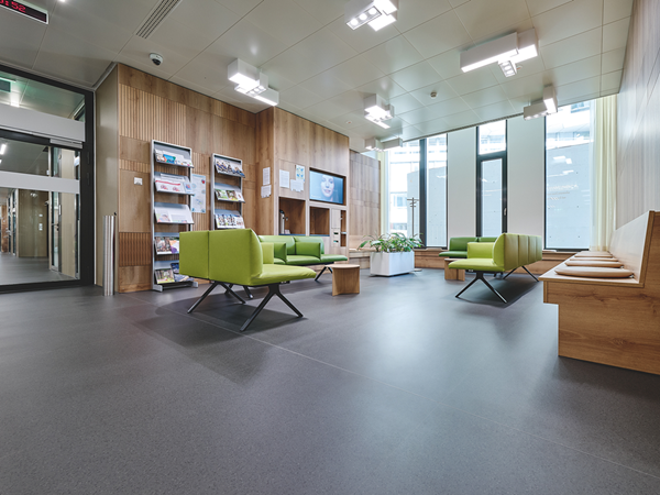 Waiting area in hospital, wood, the dark noracare seneo floor and green seat upholstery characterize the ambience
